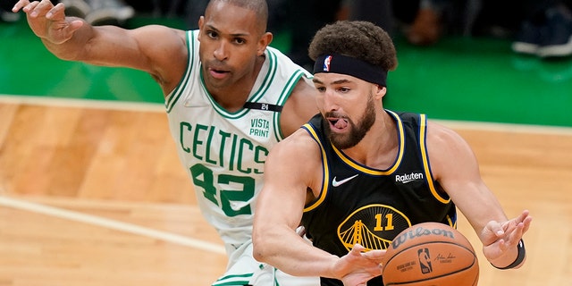Golden State Warriors guard Klay Thompson passes the ball against Boston Celtics center Al Horford in the NBA Finals, Friday, June 10, 2022, in Boston.
