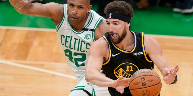 Golden State Warriors guard Klay Thompson passes the ball against Boston Celtics center Al Horford in the NBA Finals, Friday, June 10, 2022, in Boston.