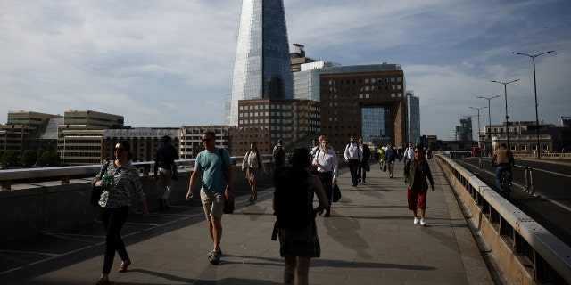 Commuters walk over London Bridge during warm weather in London, Britain, June 17, 2022.