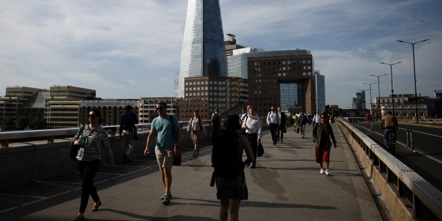 Commuters walk over London Bridge during warm weather in London, Britain, June 17, 2022. 