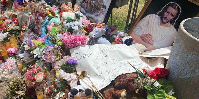 Visitors from McAllen, Texas, left a sign at the town square memorial in Uvalde. It says, "Dear children of the world, it's not supposed to be this way." 