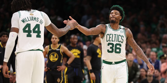 Marcus Smart and Robert Williams III of the Celtics react to a play against the Golden State Warriors during the NBA Finals at TD Garden on June 8, 2022, in Boston.