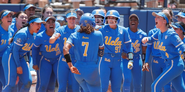UCLA's Maya Brady (7) is met by her team at home plate after a home run during the seventh inning of an NCAA softball Women's College World Series game against Oklahoma on Monday, June 6, 2022, in Oklahoma City. UCLA won 7-3.