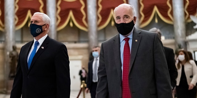 After midnight on Jan. 7, 2021, following the attack on the Capitol, Vice President Mike Pence, left, is escorted to the House chamber by Senate Sergeant at Arms Michael Stenger, as lawmakers return to complete the certification of electors in the 2020 presidential election, at the Capitol in Washington. 