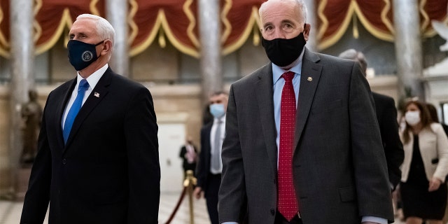 After midnight on Jan. 7, 2021, following the attack on the Capitol, Vice President Mike Pence, left, is escorted to the House chamber by Senate Sergeant at Arms Michael Stenger, as lawmakers return to complete the certification of electors in the 2020 presidential election, at the Capitol in Washington.