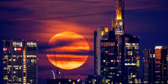 The full moon rises behind buildings in the banking district in Frankfurt, Germany, late Tuesday, June 14, 2022.