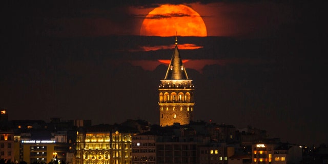 A supermoon rises behind the Galata Tower in Istanbul, Turkey, Tuesday, June 14, 2022.
