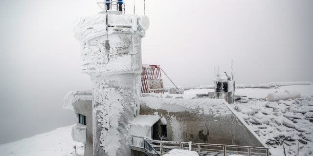 Mount Washington Observatory weather observers check on the weather instruments at the top of the observatory on the summit of Mount Washington, New Hampshire.