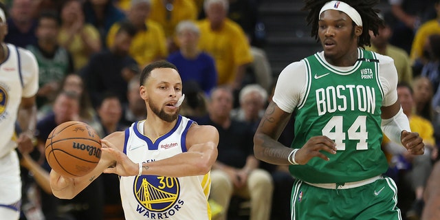 Golden State Warriors guard Stephen Curry (30) passes the ball past Boston Celtics center Robert Williams III (44) during the first half of Game 1 of the NBA Basketball Finals in San Francisco on Thursday 2 June 2022. 