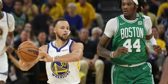 Golden State Warriors guard Stephen Curry (30) passes the ball in front of Boston Celtics center Robert Williams III (44) during the first half of Game 1 of basketball's NBA Finals in San Francisco, Thursday, June 2, 2022.