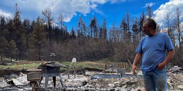 Daniel Encinias stands next to the ruins of his home destroyed by the Hermits Peak Calf Canyon fire in Tierra Monte, New Mexico, June 9, 2022.