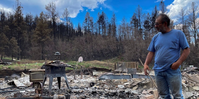 Daniel Encinias stands next to the ruins of his home destroyed by the Hermits Peak Calf Canyon fire in Tierra Monte, New Mexico, June 9, 2022.