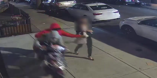 The individual riding on the back of the moped is seen grabbing the victim's purse.