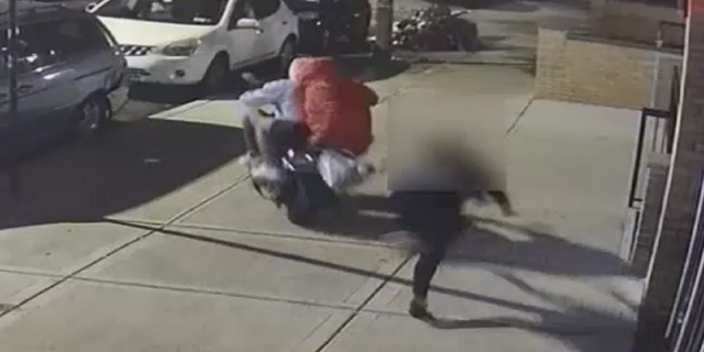 The woman appears to attempt to hold onto the purse, but ultimately loses control and is thrown to the ground.
