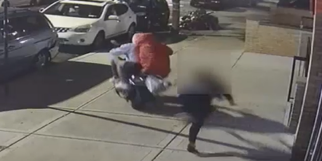 The woman appears to attempt to hold onto the purse, but ultimately loses control and is thrown to the ground.