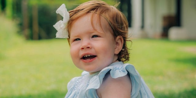 The Duke and Duchess of Sussex shared the first photo of daughter Lilibet smiling in a blue dress with a white bow in her bright red hair