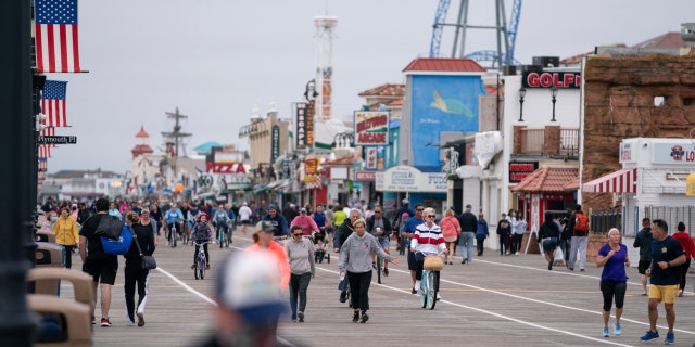 Crowds of people ride bikes and walk along the boardwalk after COVID-19 restrictions were lifted in time for the Memorial Day weekend in Ocean City, N.J., May 25, 2020. 