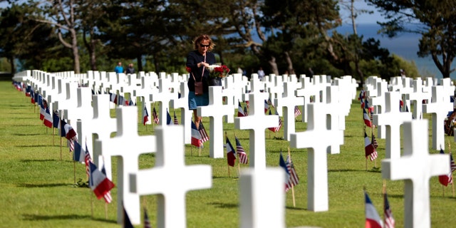 A woman holds a bouquet of roses during the 78th anniversary of D-Day ceremony, in the Normandy American Cemetery and Memorial of Colleville-sur-Mer, overlooking Omaha Beach, Monday, June, 6, 2022.