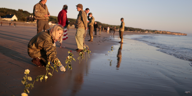 World War II reenactors put roses and flowers at dawn on Omaha Beach, in Saint-Laurent-sur-Mer, Normandy, France on Monday, June 6.