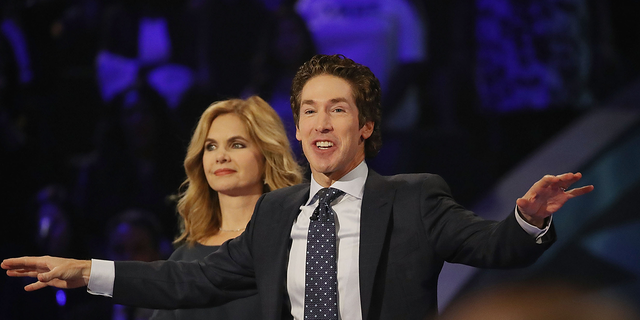 Joel Osteen, the pastor of Lakewood Church, stands with his wife, Victoria Osteen, as he conducts a service.