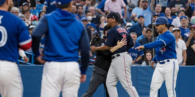 Boston Red Sox third baseman Rafael Devers (11) is held back by an umpire during a heated exchange after Toronto Blue Jays' Alejandro Kirk was hit by a pitch during the fourth inning of a baseball game Wednesday, June 29, 2022, in Toronto. 