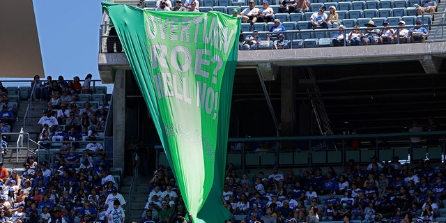 Security personnel remove a banner that reads, "Overturn Roe? Hell No!" during the Los Angeles Dodgers-New York Mets game on June 5, 2022, in LA.