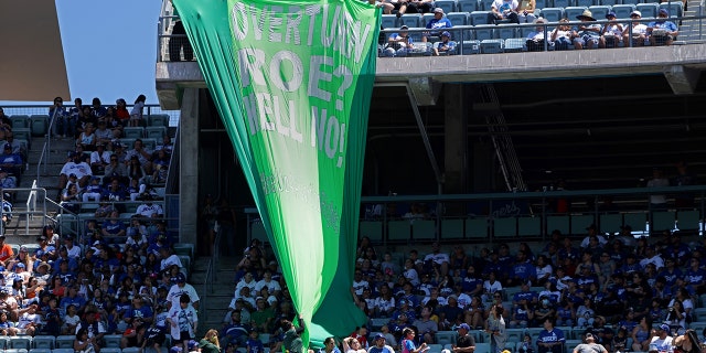 Security personnel remove a banner that reads, "Overturn Roe? Hell No!" during the Los Angeles Dodgers-New York Mets game on June 5, 2022, in LA.