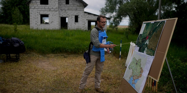 A mine detection worker with the HALO Trust de-mining NGO explains how they search for anti-tank and anti-personnel land mines in Lypivka, on the outskirts of Kyiv, Ukraine, Tuesday, June 14, 2022. 