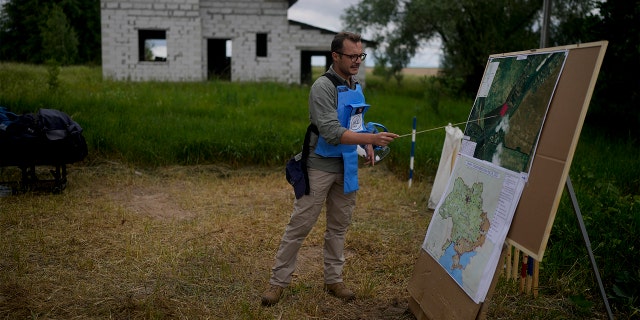 A mine detection worker with the HALO Trust de-mining NGO explains how they search for anti-tank and anti personnel land mines in Lypivka, on the outskirts of Kyiv, Ukraine, Tuesday, June 14, 2022.