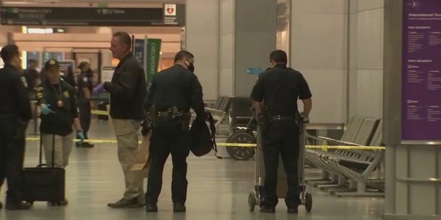 Police at San Francisco International Airport were seen after a man injured three people in an attack with an "edged weapon" Friday, June 17, 2022, officials said. One officer put a backpack into a brown paper bag.