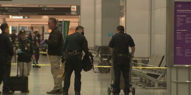 Police at San Francisco International Airport were seen after a man injured three people in an attack with an "edged weapon" Friday, June 17, 2022, officials said. One officer put a backpack into a brown paper bag.