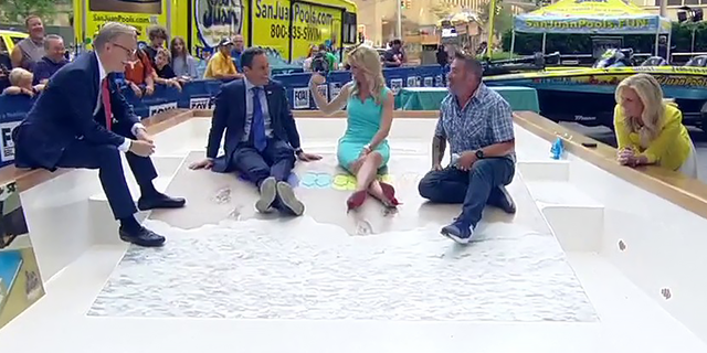 "Fox and Friends" co-hosts and home improvement expert Skip Bedell dip their toes in the water, so to speak, of San Juan Pool's Baja Beach 3D-printed fiberglass pool model at Fox Square, on June 29, 2022. (Fox News)