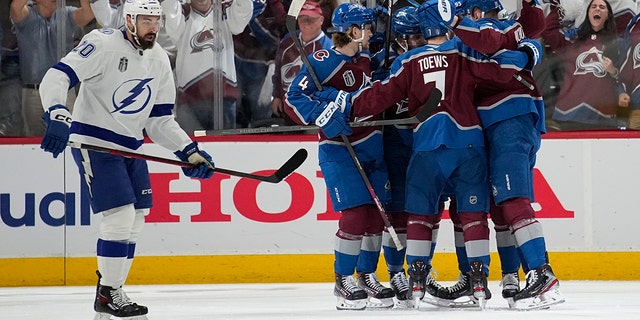 Colorado Avalanche players celebrate a goal by Valeri Nichushkin as Tampa Bay Lightning left wing Nicholas Paul, left, skates past during the first period in Game 2 of the NHL hockey Stanley Cup Final on Saturday, June 18, 2022, in Denver. (AP Photo/John Locher)