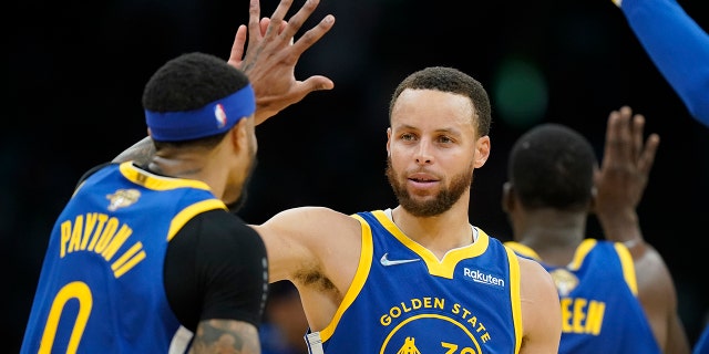 Golden State Warriors guard Stephen Curry (30) high fives Golden State Warriors guard Gary Payton II (0) during the second quarter of Game 6 of basketball's NBA Finals against the Boston Celtics, Thursday, June 16, 2022, in Boston.