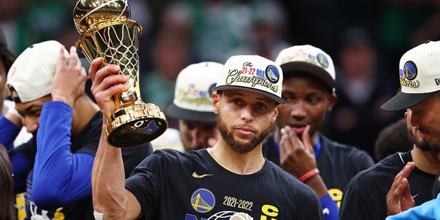 Stephen Curry #30 of the Golden State Warriors raises the Bill Russell NBA Finals Most Valuable Player Award after defeating the Boston Celtics 103-90 in Game Six of the 2022 NBA Finals at TD Garden on June 16, 2022 in Boston, Massachusetts.