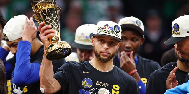 Stephen Curry #30 of the Golden State Warriors raises the Bill Russell NBA Finals Most Valuable Player Award after defeating the Boston Celtics 103-90 in Game Six of the 2022 NBA Finals at TD Garden on June 16, 2022 in Boston, Massachusetts.