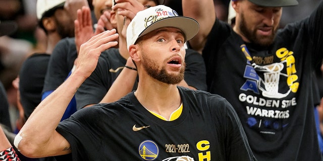 Golden State Warriors guard Stephen Curry celebrates with teammates as he holds the Bill Russell Trophy for Most Valuable Player after the Warriors beat the Boston Celtics in Game 6 to win basketball's NBA Finals, Thursday, June 16, 2022, in Boston.