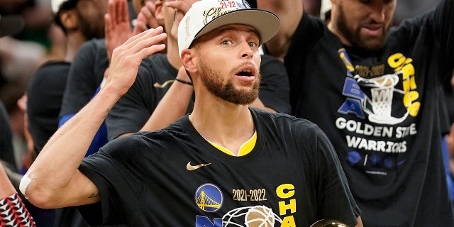 Golden State Warriors guard Stephen Curry celebrates with teammates as he holds the Bill Russell Trophy for Most Valuable Player after the Warriors beat the Boston Celtics in Game 6 to win basketball's NBA Finals, Thursday, June 16, 2022, in Boston.