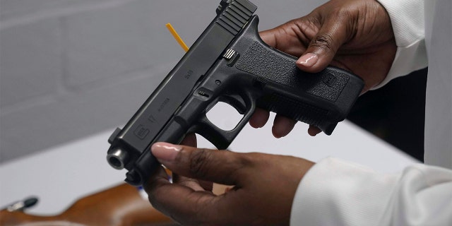 FILE - A handgun from a collection of illegal guns is reviewed during a gun buyback event in Brooklyn, N.Y., May 22, 2021. 