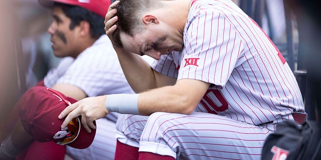 Oklahoma's Tanner Tredaway sits in the dugout following their 4-2 loss against Mississippi in Game 2 of the NCAA College World Series baseball finals, Sunday, June 26, 2022, in Omaha, Neb. Mississippi defeated Oklahoma 4-2 to win the championship. 