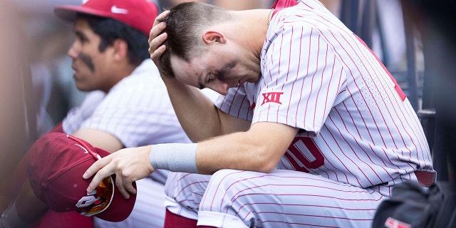 Oklahoma's Tanner Tredaway sits in the dugout following their 4-2 loss against Mississippi in Game 2 of the NCAA College World Series baseball finals, Sunday, June 26, 2022, in Omaha, Neb. Mississippi defeated Oklahoma 4-2 to win the championship.