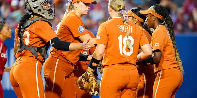 The Texas Longhorns meet at the pitching circle during the game against the Oklahoma Sooners during the Division I Women's Softball Championship held at ASA Hall of Fame Stadium on June 9, 2022 in Oklahoma City, Oklahoma.