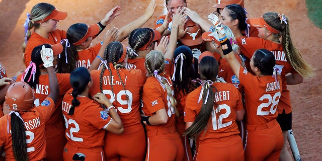 Texas Longhorns first baseman Courtney Day #15 is knocked on the head by her teammates after hitting a solo home run against the Arizona Wildcats in the third inning during the NCAA Women's College World Series at the USA Softball Hall of Fame Complex on 5 June , 2022 in Oklahoma City, Oklahoma.