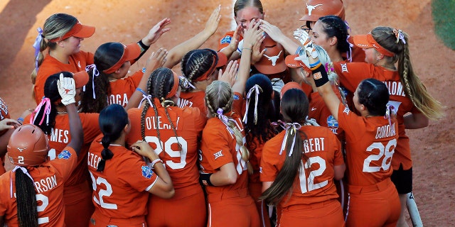 First baseman Courtney Day #15 of the Texas Longhorns is patted on the head by her teammates after hitting a solo home run against the Arizona Wildcats in the third inning during the NCAA Women's College World Series at the USA Softball Hall of Fame Complex on June 5, 2022 in Oklahoma City, Oklahoma.