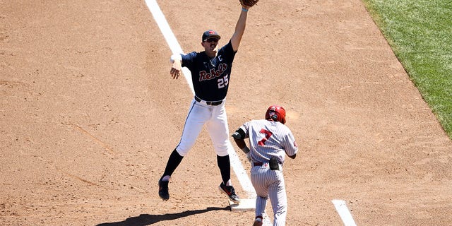 Tim Elko #25 of the Ole Miss Rebels leaps for a throw while Kendall Pettis #7 of the Oklahoma Sooners runs to first base during the sixth inning during the Division I Men's Baseball Championship held at Charles Schwab Field Omaha on June 26, 2022 in Omaha, Nebraska. 