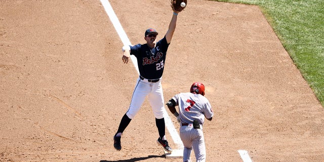 Tim Elko #25 of the Ole Miss Rebels leaps for a throw while Kendall Pettis #7 of the Oklahoma Sooners runs to first base during the sixth inning during the Division I Men's Baseball Championship held at Charles Schwab Field Omaha on June 26, 2022 in Omaha, Nebraska.