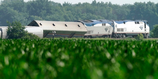 The derailed Amtrak train is seen beyond a cornfield on Tuesday, June 28, 2022, near Mendon, Mo. The train derailed after hitting a dump truck on Monday killing the truck driver and other people on the train and injuring several dozen other passengers on the Chicago-bound train.