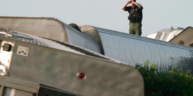 A law enforcement officer inspects the scene of the Amtrak train derailment on Monday; the train derailed after striking a dump truck on June 27, 2022, near Mendon, Mo.