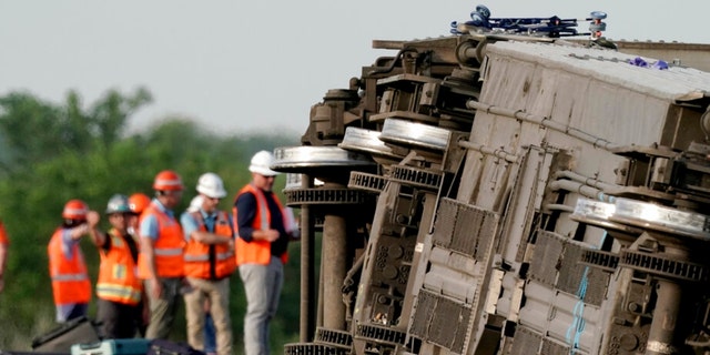 Workers inspect the scene of an Amtrak train which derailed after striking a dump truck Monday, June 27, 2022, near Mendon, Mo. 