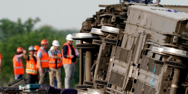 Workers inspect the scene of an Amtrak train which derailed after striking a dump truck Monday, June 27, 2022, near Mendon, Mo.